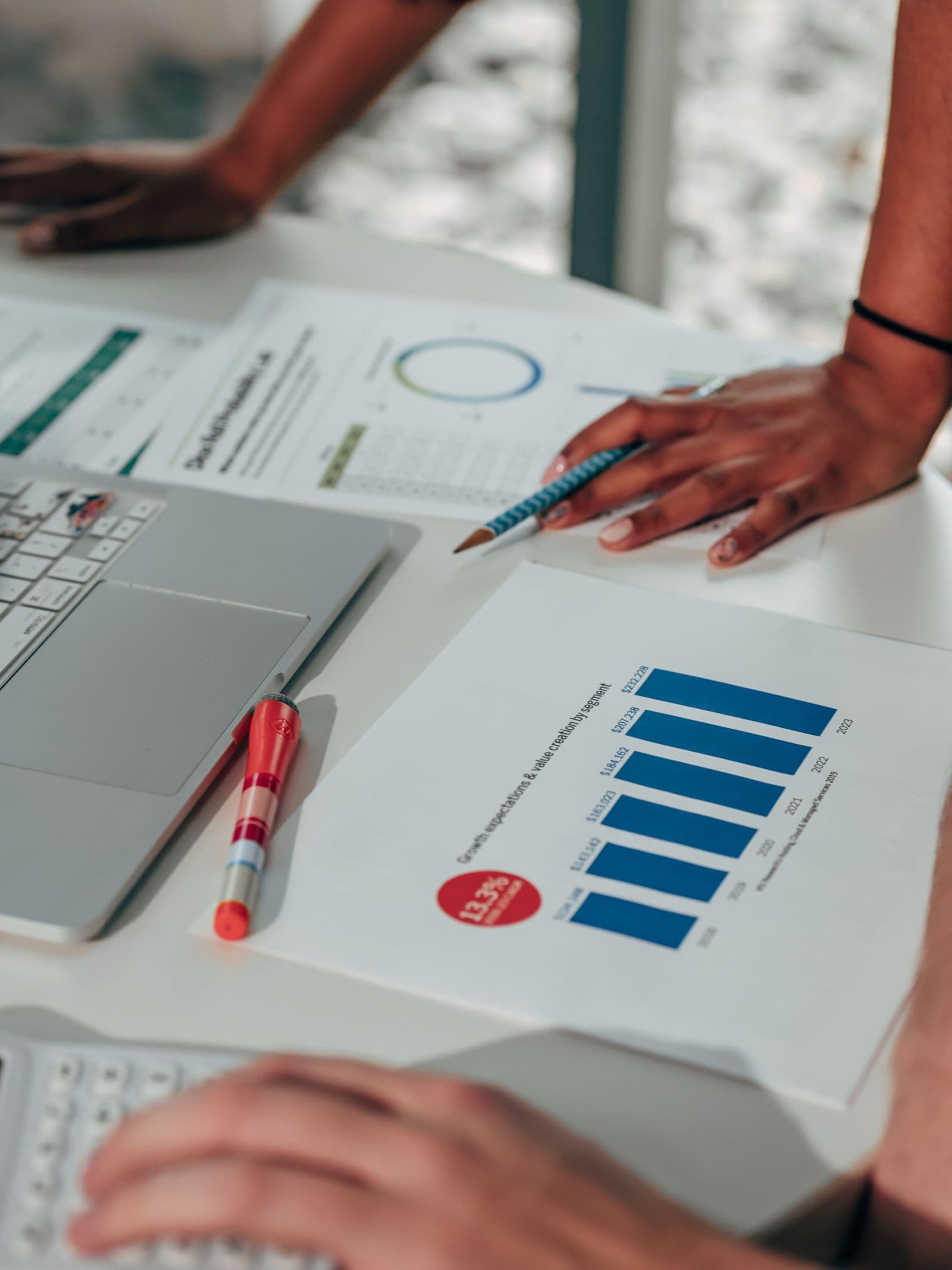 People reviewing printed charts beside laptops at a shared workspace; illustrative stock photograph.
