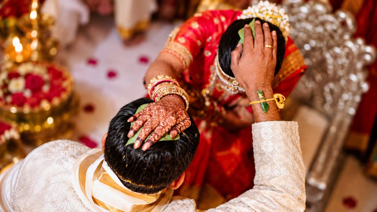 A bride and groom during a Hindu wedding ritual, hands raised in blessing.