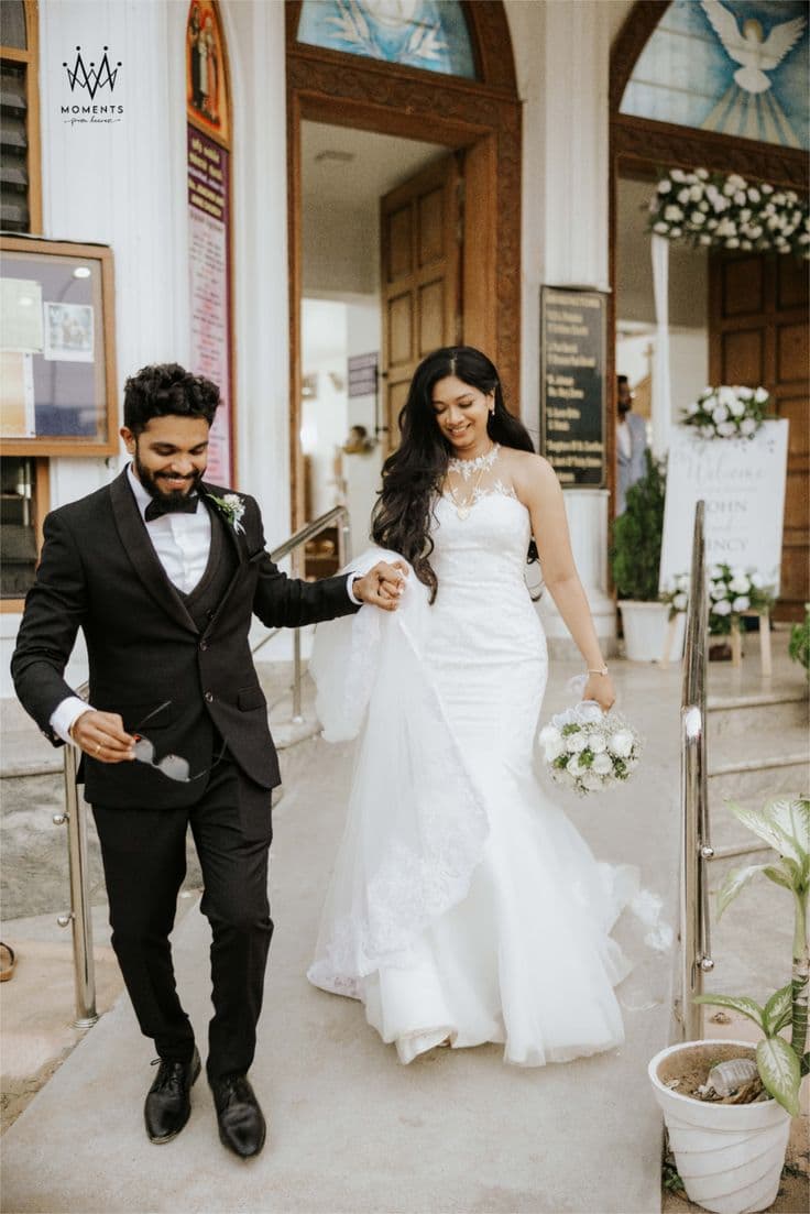 A bride in a white gown and a groom in a black suit leaving a church together.